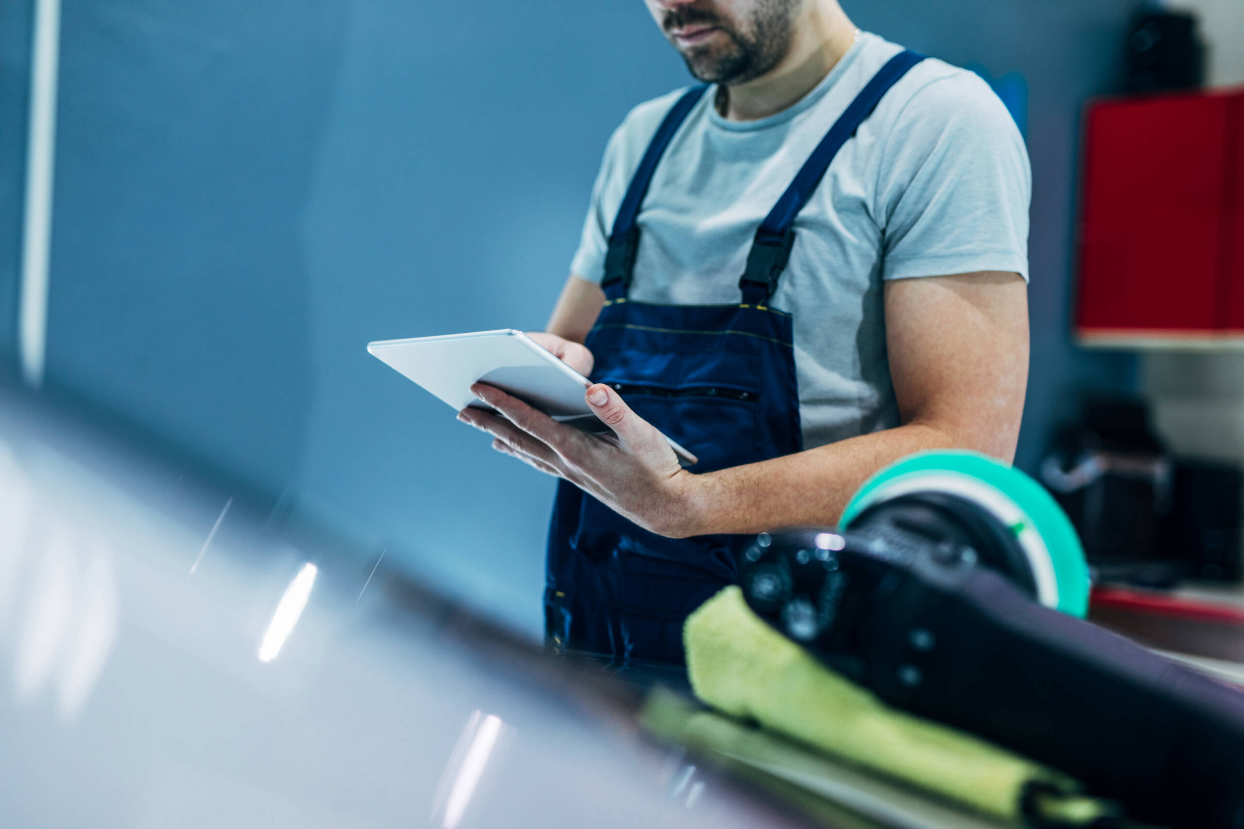 Carrozziere Croce Auto Group durante la verifica digitale della checklist 50 punti su tablet in officina moderna, con monitoraggio qualità e sicurezza.