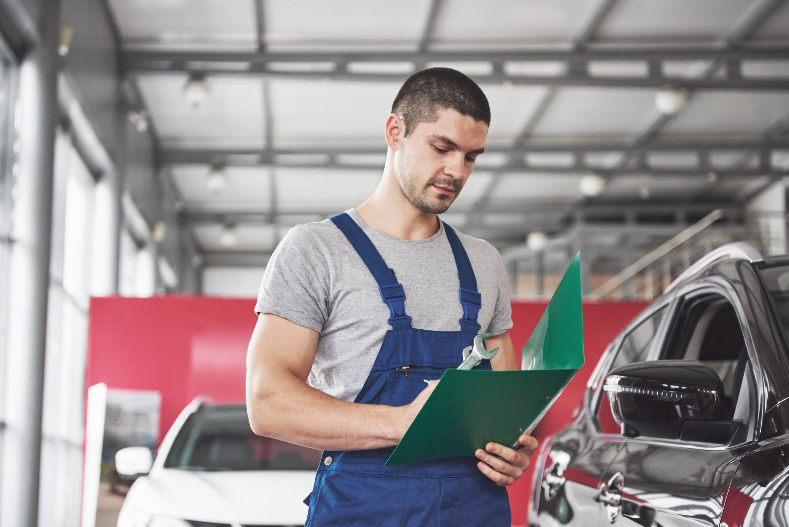 Tecnico carrozziere Croce Auto Group mentre verifica e compila manualmente la checklist di controllo qualità 50 punti su modulo cartaceo, in officina professionale.